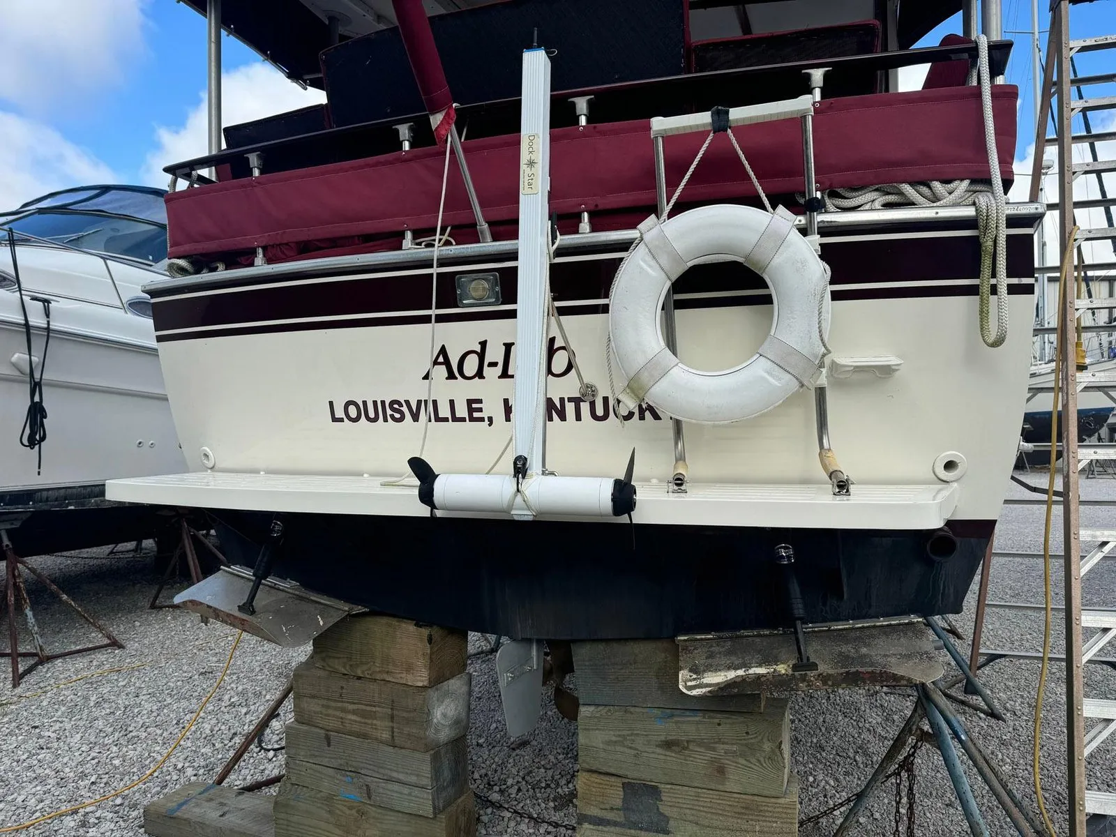 A boat on the hard with a DockStar unit strapped to a white vertical track on the transom, above the swim platform. The hull below it is unbroken — no through-hull fitting anywhere near the unit.