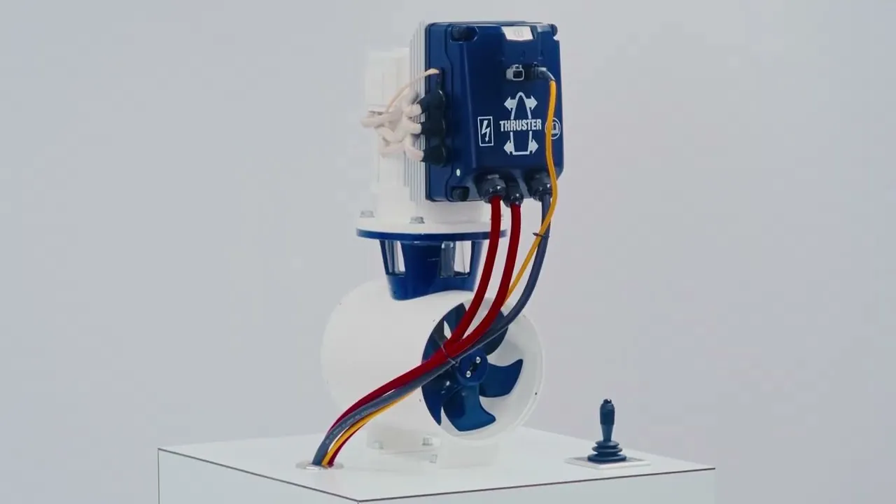 A still from VETUS's BOW PRO video: a white tunnel thruster with its blue controller box and propeller on a stand, a joystick beside it.